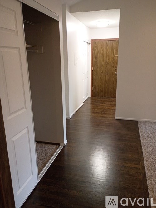 A hallway with a white door on the left and a wooden door on the right.