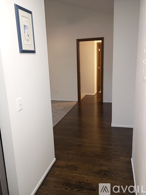 A hallway with a wooden floor and a door at the end.
