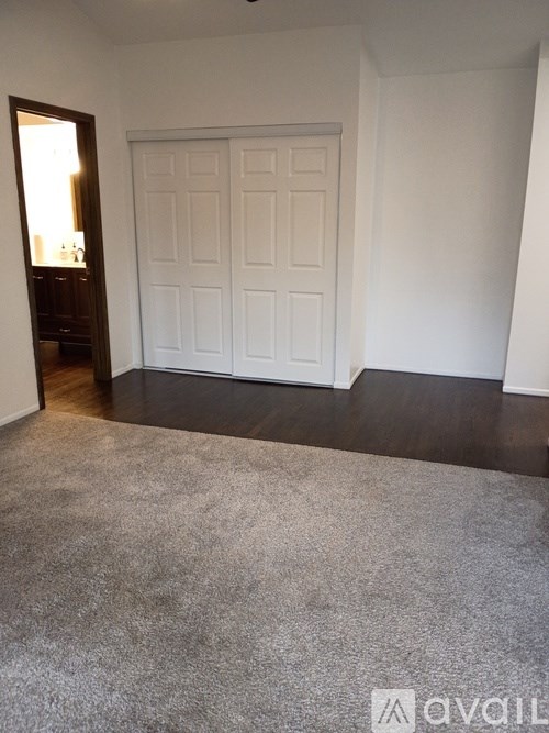 A room with a white door and a grey carpet.
