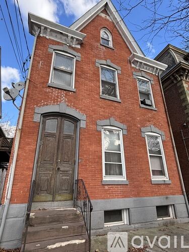 A red brick house with a black door and a small porch.