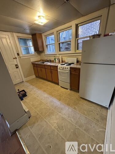 A kitchen with a white refrigerator, white stove, and brown cabinets.