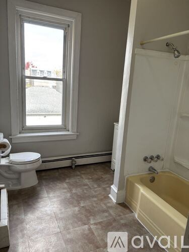 A bathroom with a toilet, tub, and window.