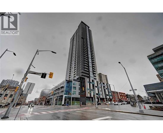 A tall building stands in the middle of a city intersection.