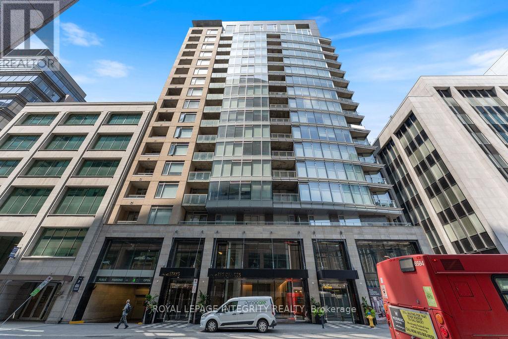 A tall building with a glass facade stands in front of a red double-decker bus.