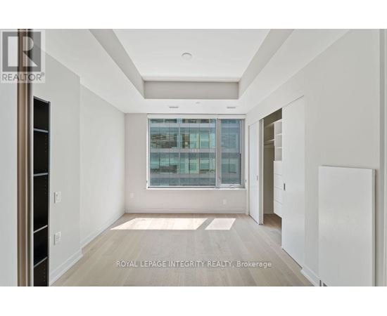 A spacious, empty room with a large window and a view of a cityscape.