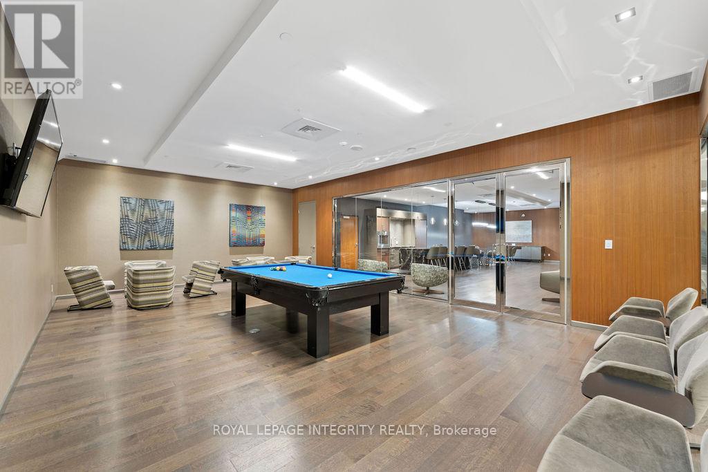 A pool table is surrounded by chairs in a room with wood flooring.