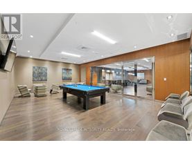 A pool table is surrounded by chairs in a room with wood flooring.