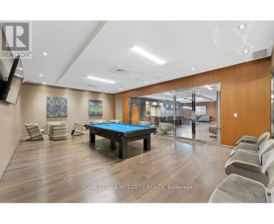 A pool table is surrounded by chairs in a room with wood flooring.