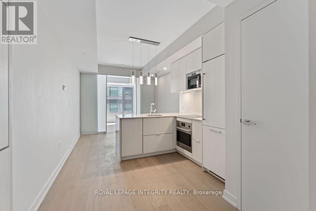 A spacious kitchen with white cabinets and a wooden floor.