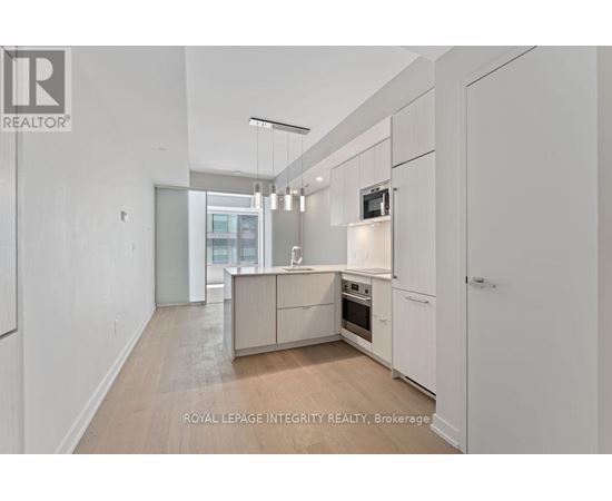 A spacious kitchen with white cabinets and a wooden floor.
