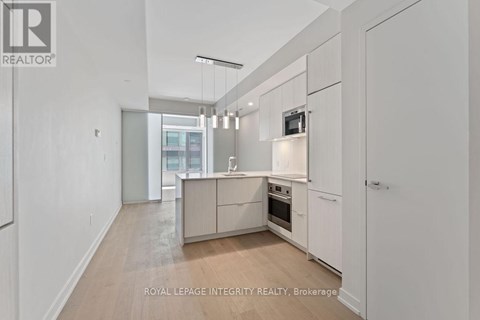 A spacious kitchen with white cabinets and a wooden floor.