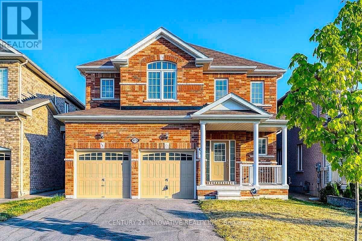 A brick house with a garage and a tree in front.