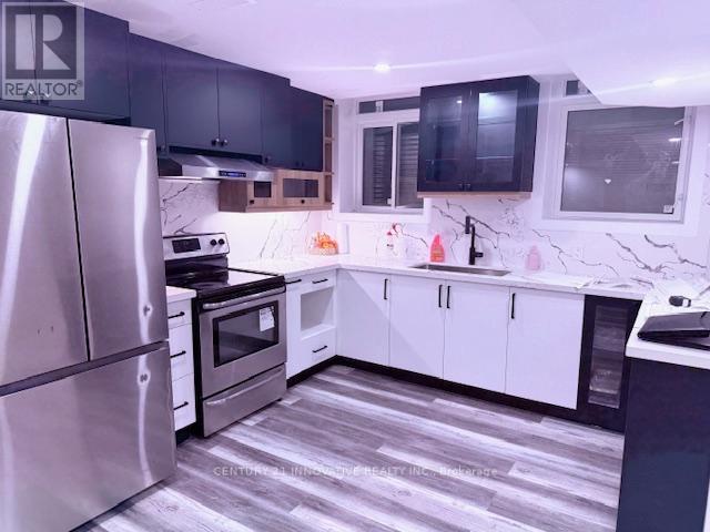 A modern kitchen with a stainless steel refrigerator and black cabinets.