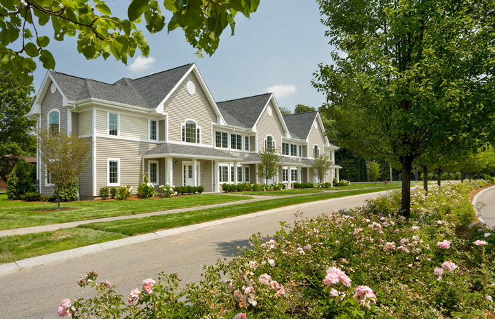 a house on a street with flowers in front of it