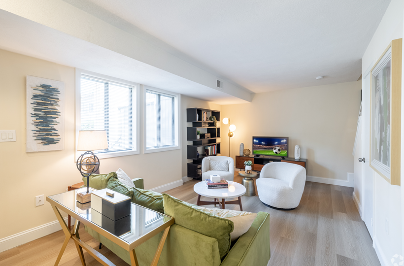 A living room with a green couch and a glass coffee table.