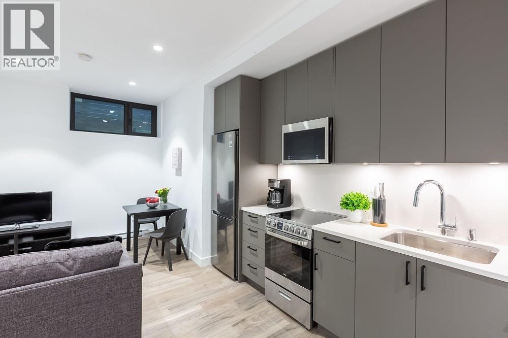 A modern kitchen with a grey theme and a TV mounted on the wall.