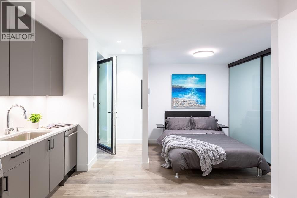 A bedroom with a bed, a sink, and a painting on the wall.