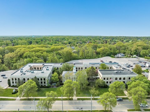 A large white building surrounded by trees and a parking lot.