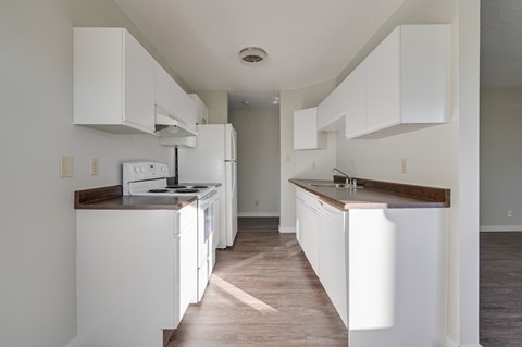 A kitchen with white cabinets and appliances.