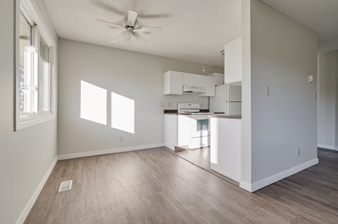 A spacious, empty room with a ceiling fan and a window.