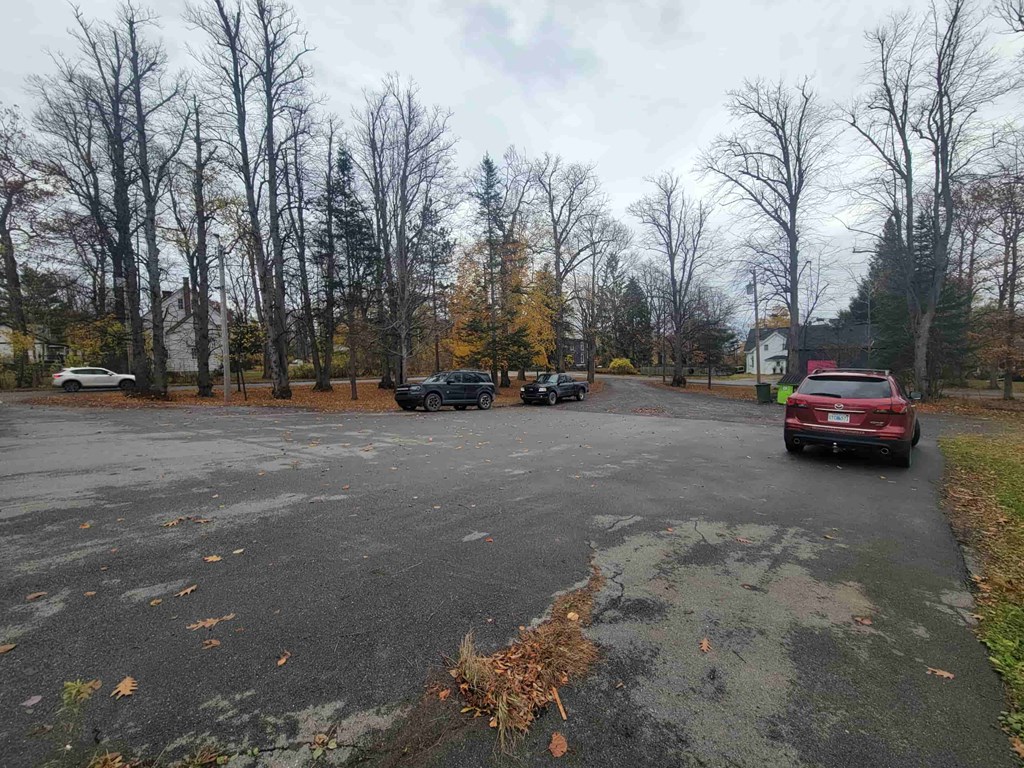 A parking lot with cars and trees in the background.