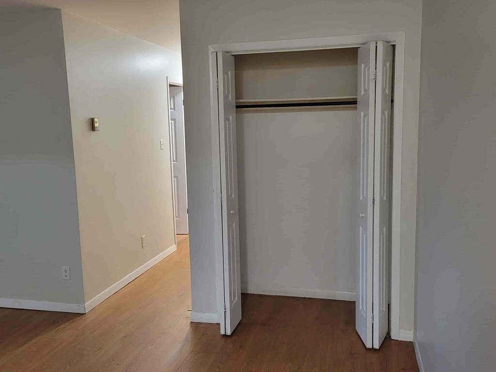A white closet with a door open in a room.