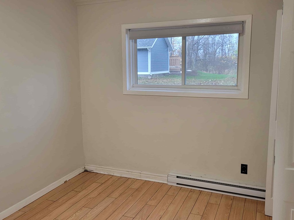 A room with a window and wooden flooring.