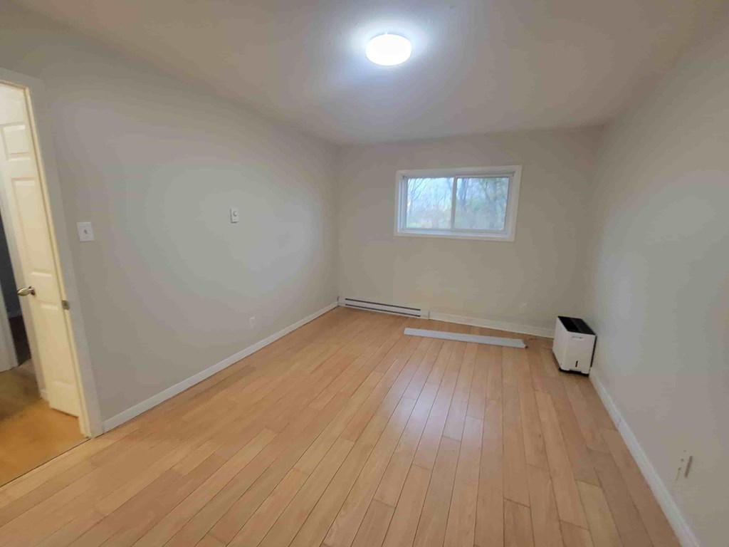 A room with wooden flooring and a window.
