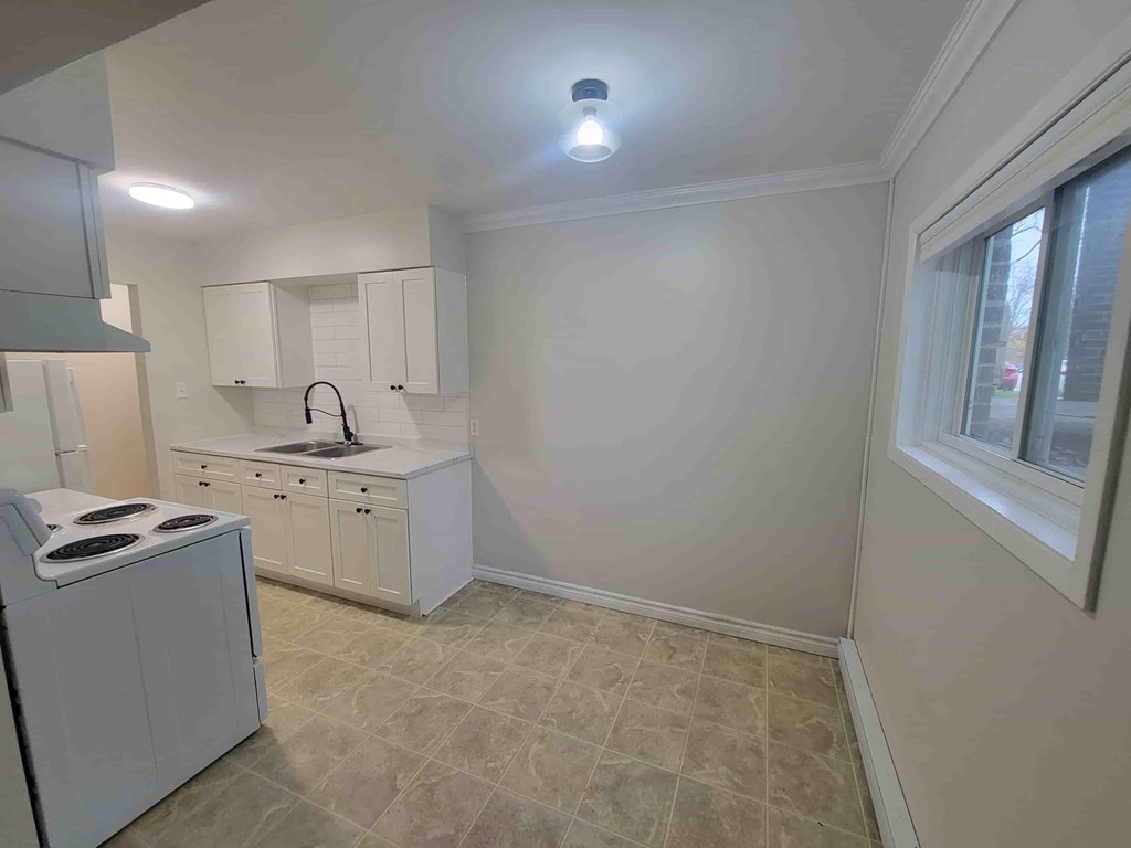 A kitchen with white cabinets and a tiled floor.