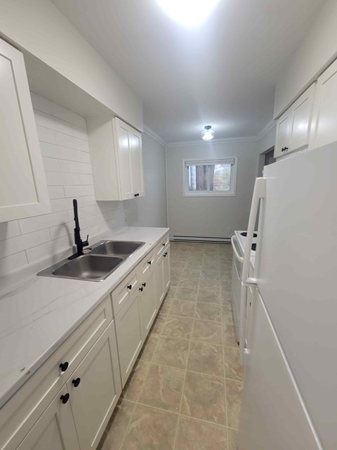 A kitchen with white cabinets and a sink.