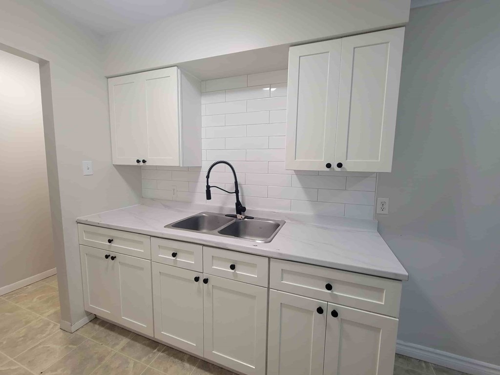 A kitchen with white cabinets and a sink.