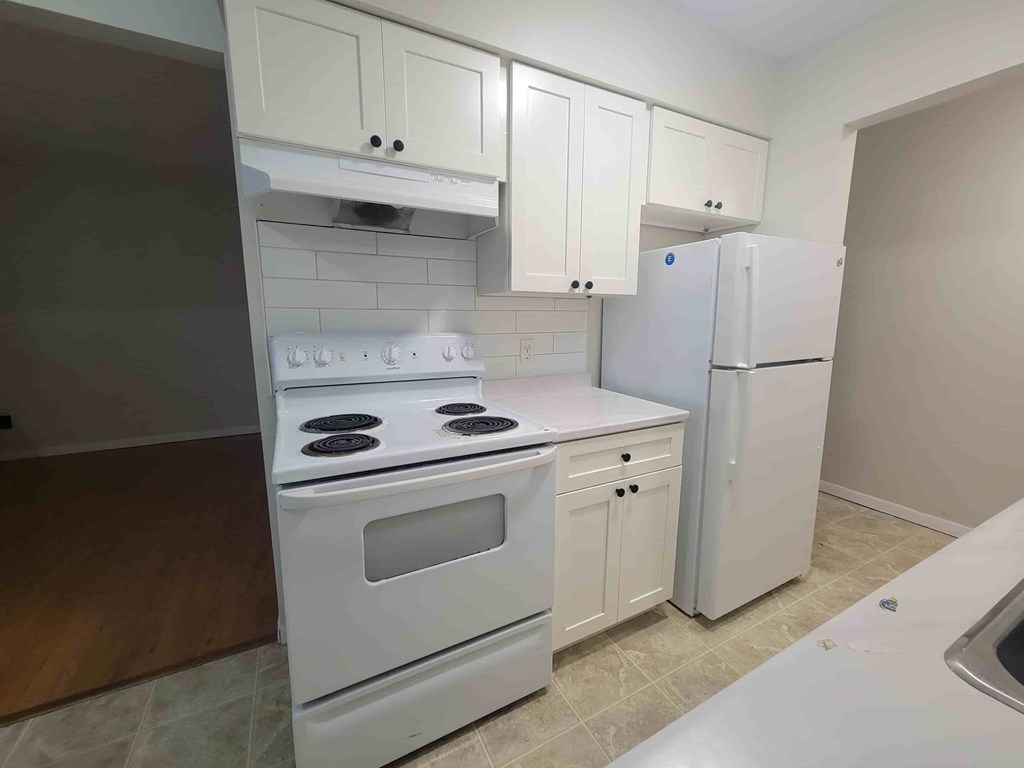 A kitchen with white appliances and cabinets.