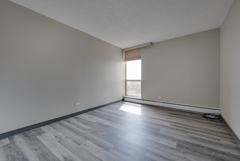 A room with wooden flooring and a window letting in sunlight.