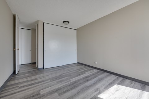 A room with a grey floor and white walls with a door and a window.