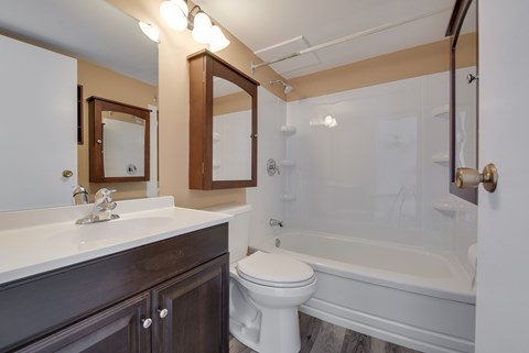A white toilet sits next to a white bathtub in a bathroom.