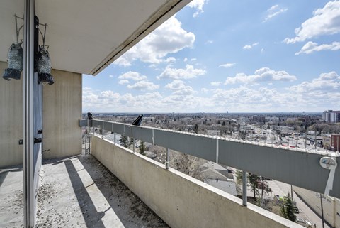 A balcony with a view of a town and the sea.