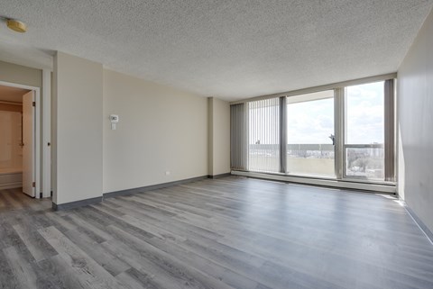 A room with a grey floor and a window overlooking a cityscape.