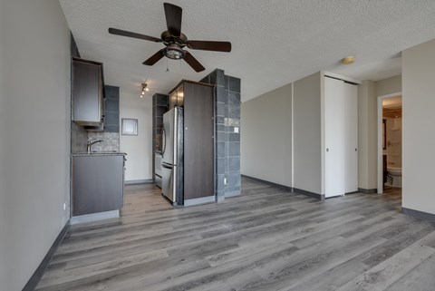 A kitchen with a fan on the ceiling and a refrigerator.