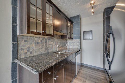 A kitchen with a granite countertop and wooden cabinets.