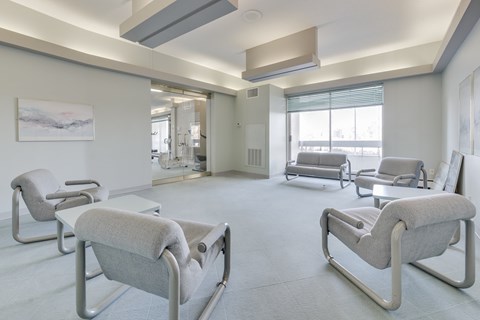 A room with white walls and grey chairs.
