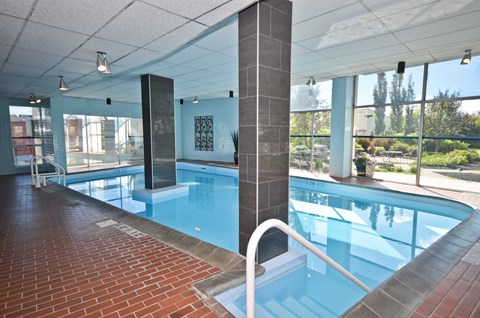A large indoor swimming pool with a brick walkway.