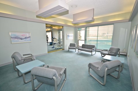 A room with a blue carpet and grey chairs.