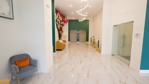 A hallway with a grey armchair and a white wall.