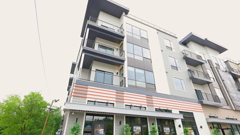 A modern multi-story building with balconies and a striped awning.