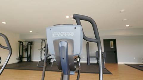 A treadmill in a gym with a black mat on the floor.