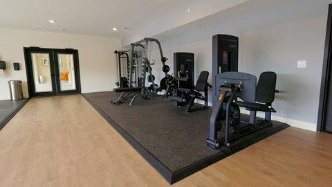 A gym with a variety of equipment including a treadmill, weights, and a bench press.