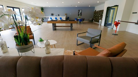 A living room with a brown couch and a table with a vase of flowers on it.