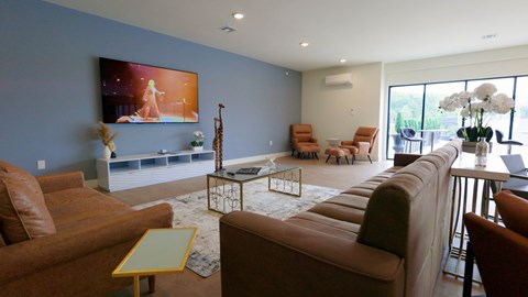 A living room with a large screen TV and comfortable seating.