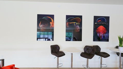 Three posters of a man wearing a hat are on a white wall.