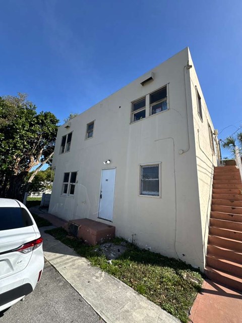 A white house with a car parked in front.